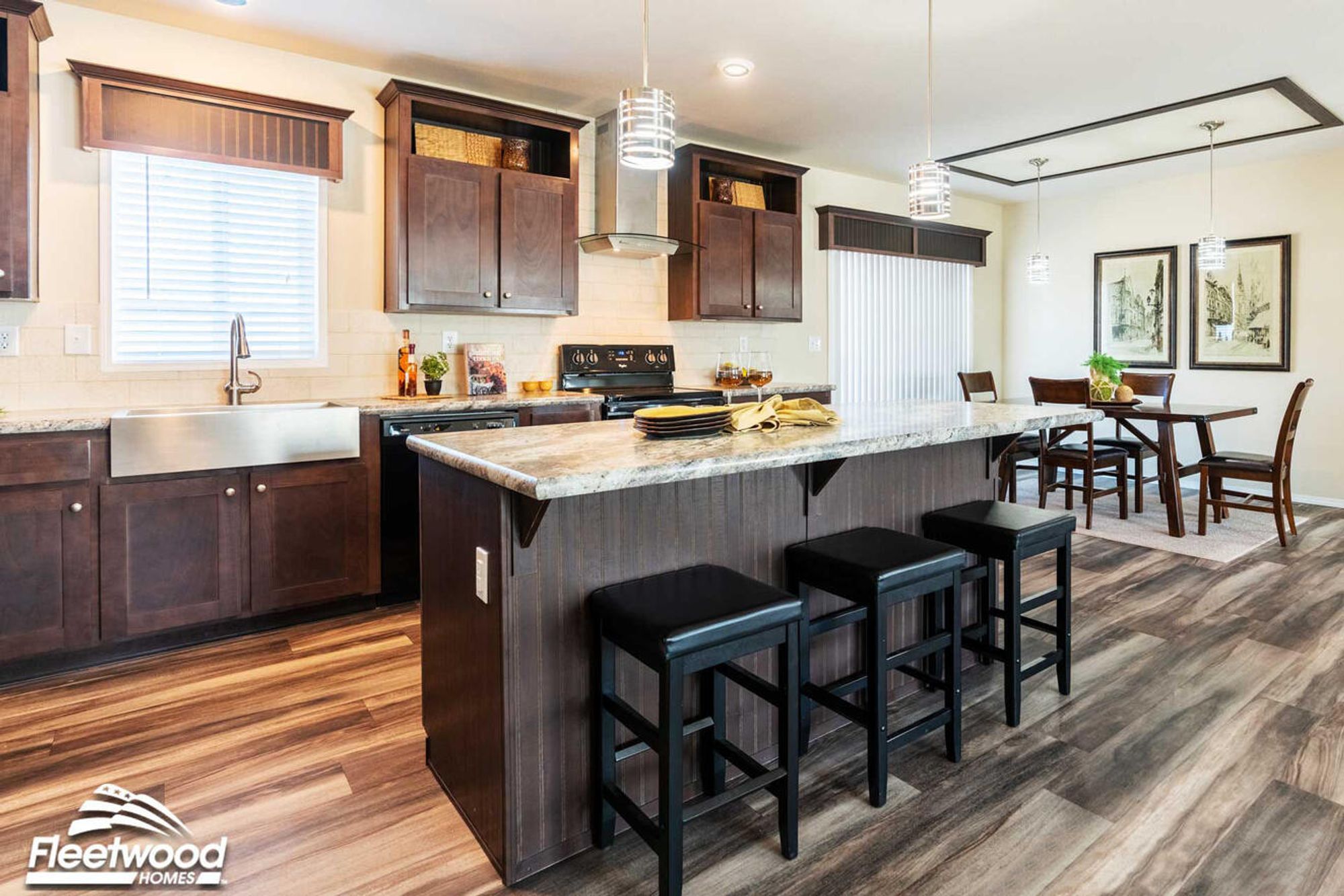 Kitchen, and living area with dark wood cabinets, center island, modern lighting.