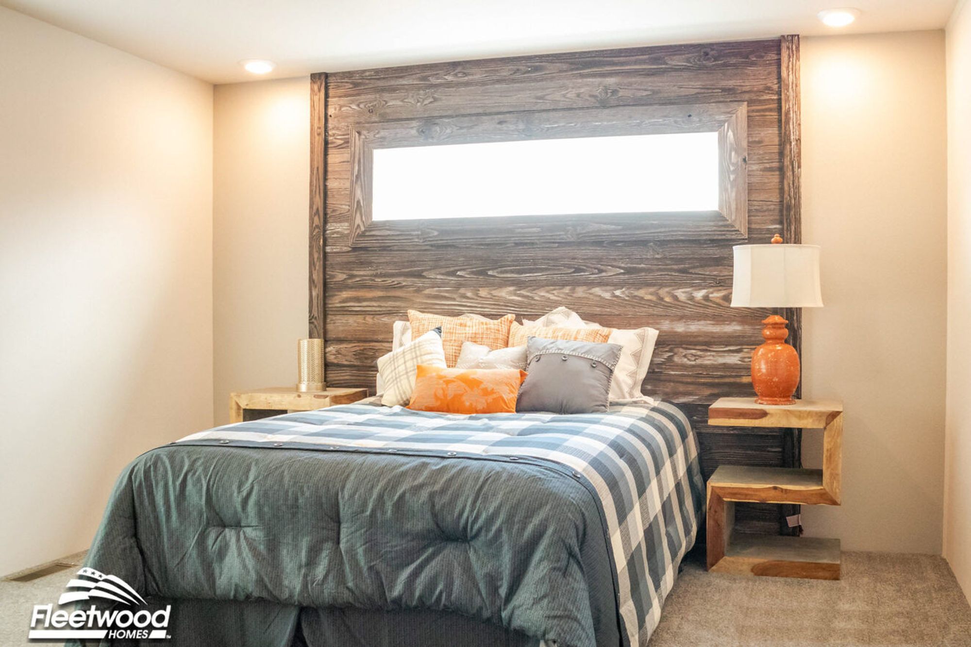 Rustic-style bedroom with a large wooden headboard, plaid bedding in shades of blue and gray, and unique wooden side tables with modern lamps.