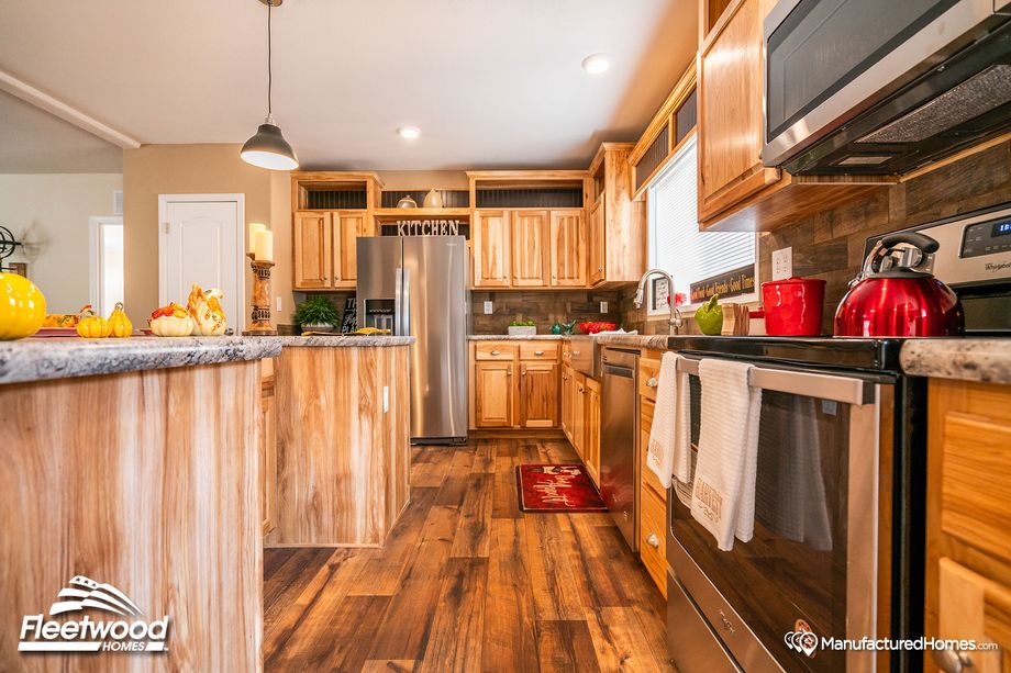 Large kitchen with a mix of light and medium warm wood cabinetry, and pepper-colored style countertops.