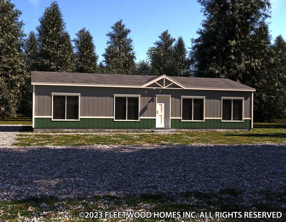 Single-story manufactured home with blue siding, dark trim accents, a white front door, and three large front windows, set on a grassy lot with trees in the background.