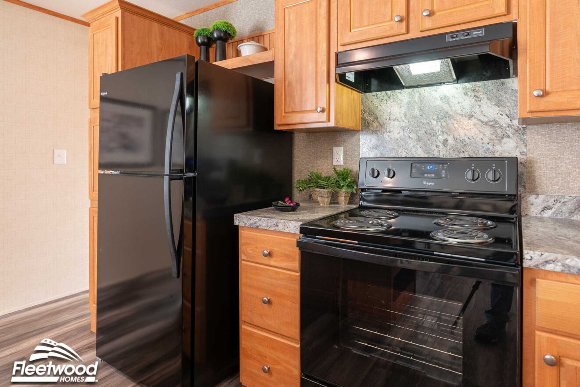 Kitchen with wood cabinets, marble-look countertops, and a black stove with matching range hood.