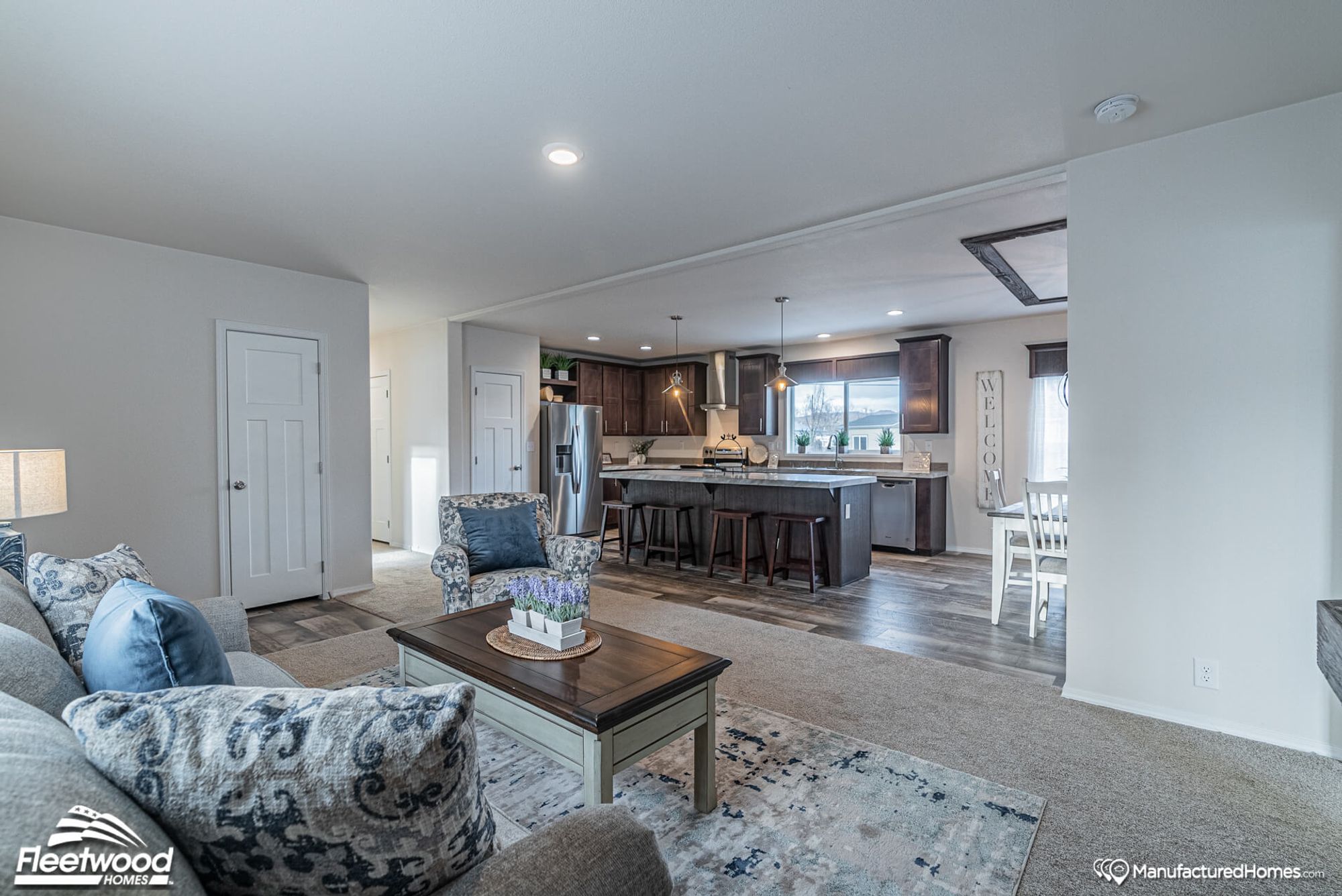 Large living room with one couch, one chair, and a coffee table, part of an open-concept area featuring a kitchen and a dining table.