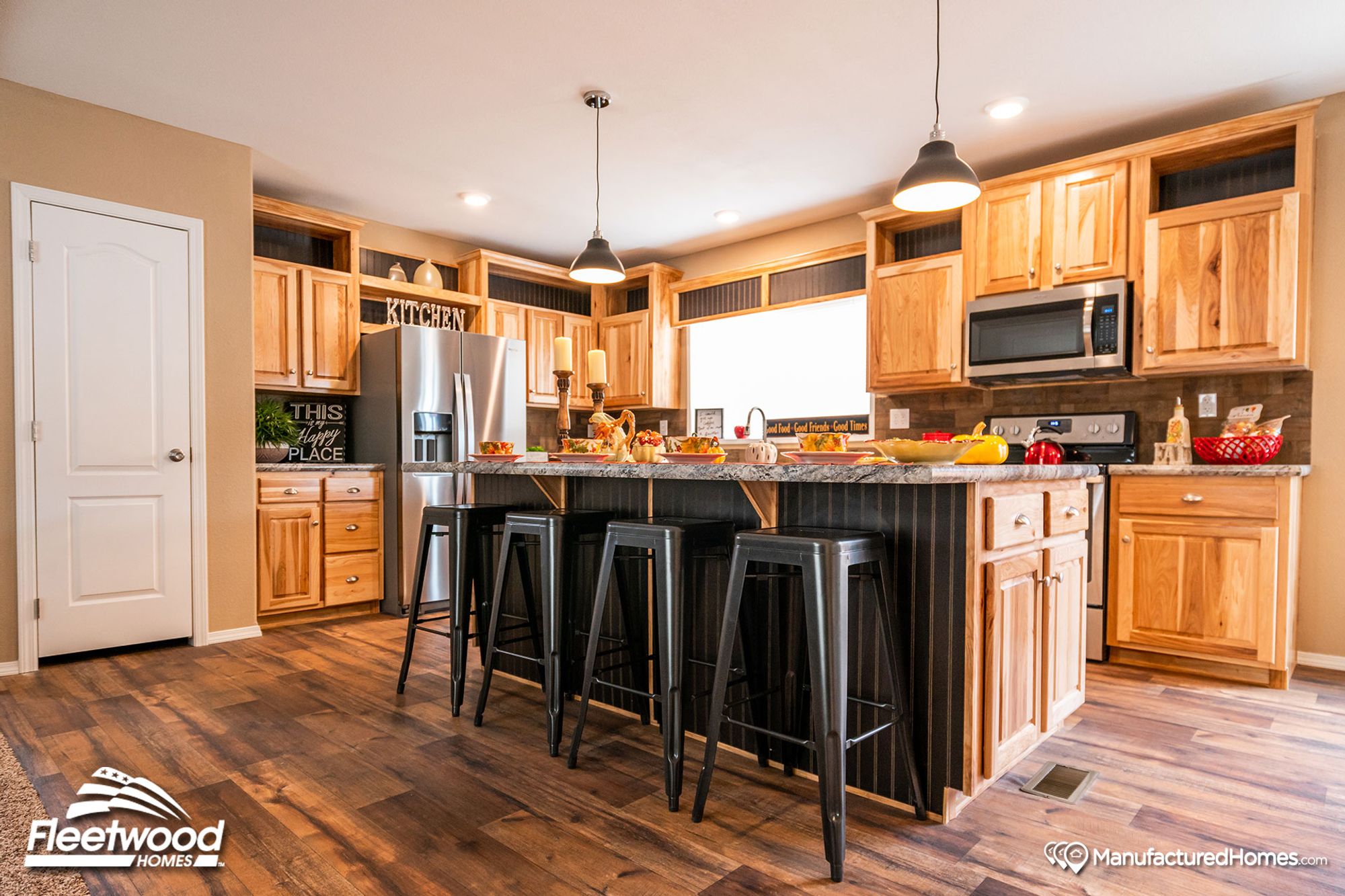 Large kitchen with a mix of light and medium warm wood cabinetry, and pepper-colored style countertops.