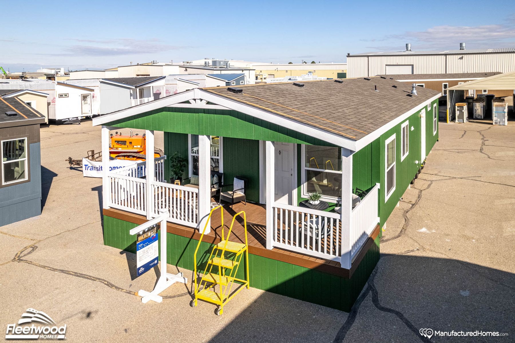 Covered front porch with green siding, outdoor seating, a small table, rug, and potted plant. White front door and railing, with neighboring homes visible in the background.