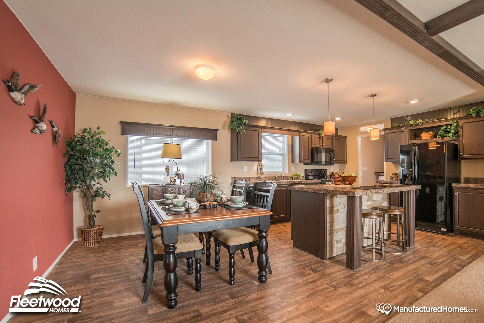 Open-concept kitchen and dining room featuring brown cabinetry and an island with two stools.