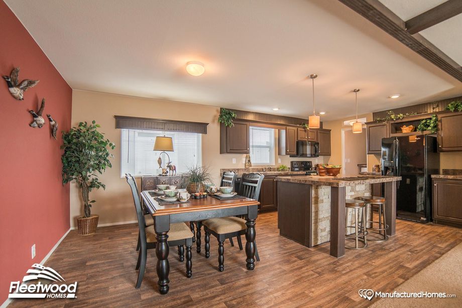 Open-concept kitchen and dining room featuring brown cabinetry and an island with two stools.