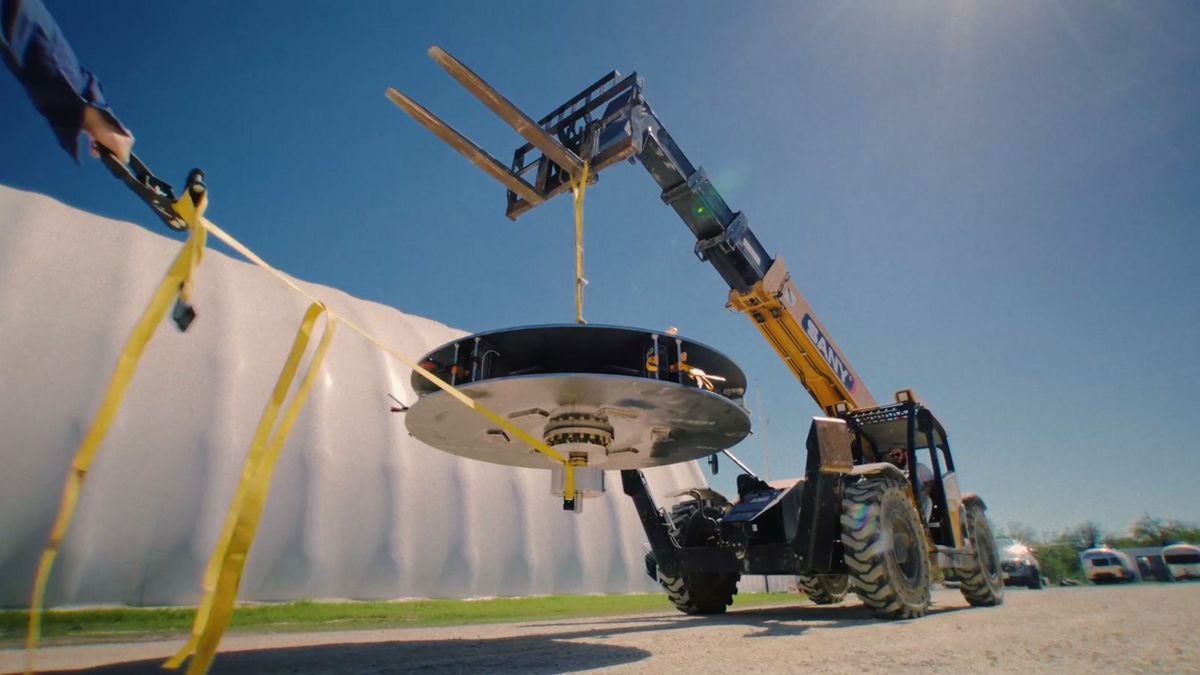 The Genesis rotor slung from a telehandler against a clear sky