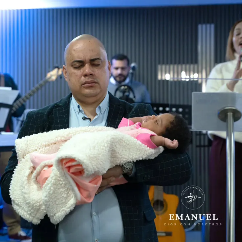 El pastor orando por una bebé en sus brazos