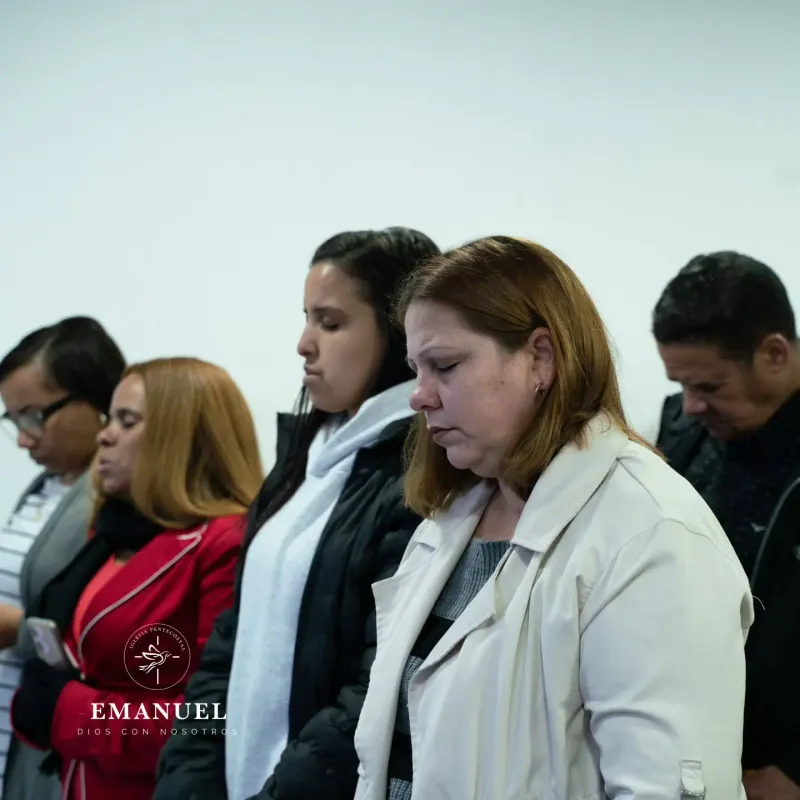 Hermanas orando con los ojos cerrados durante el culto de Pentecostés