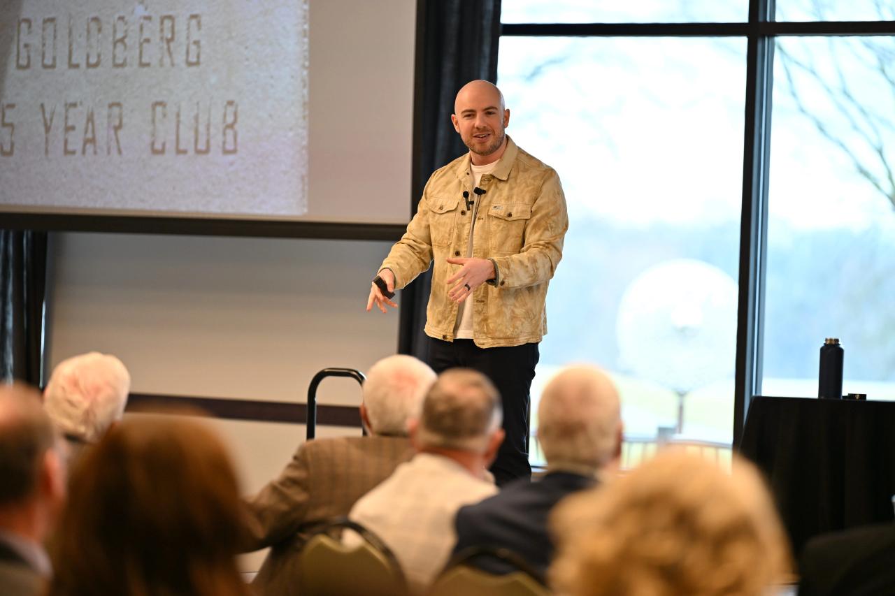 Attendees seated at round tables in a ballroom watching Danny Goldberg speak