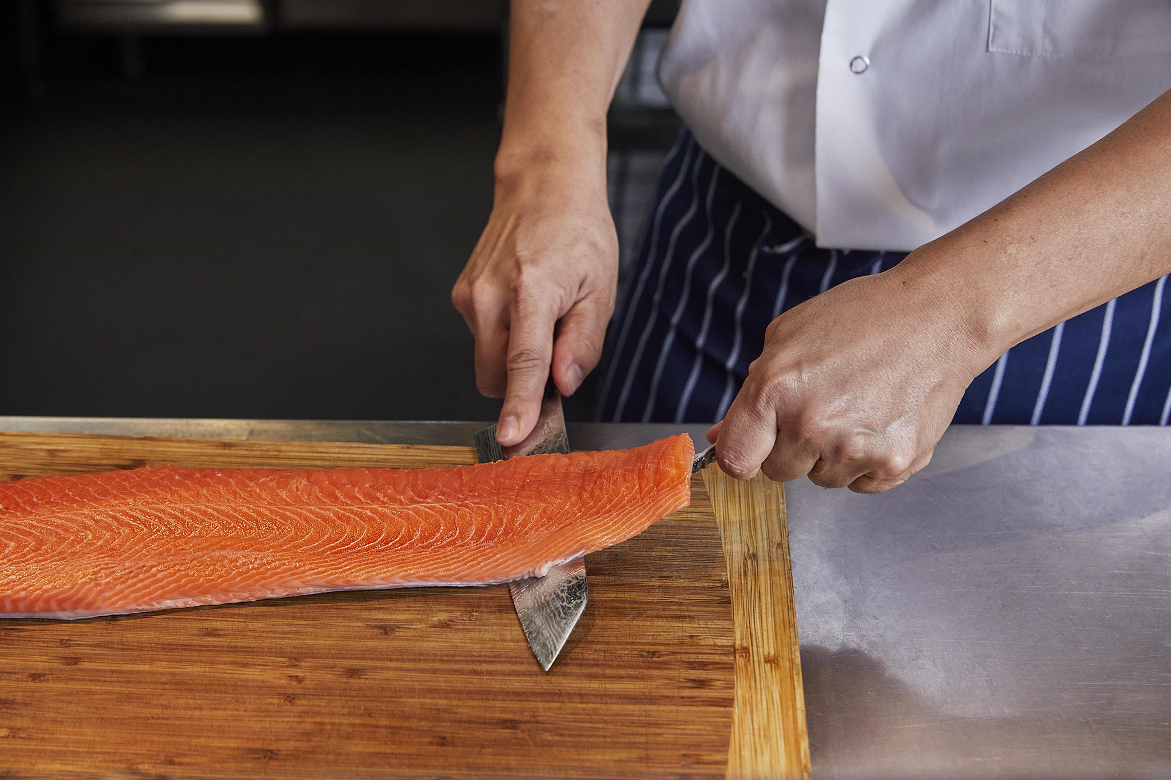 A chef deboning salmon with a Honesuki knife.