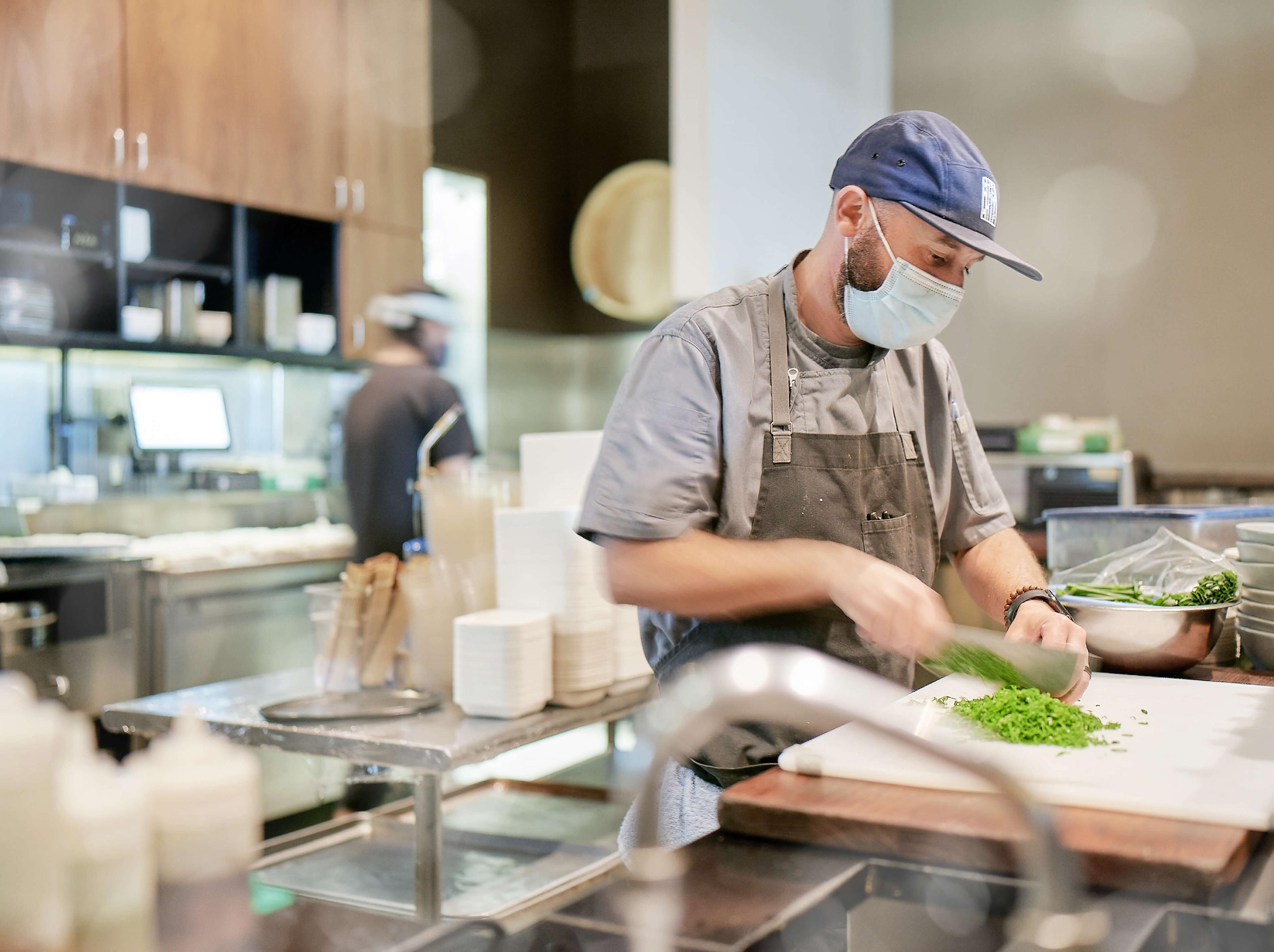 A chef prepping greens in a restaurant kitchen.