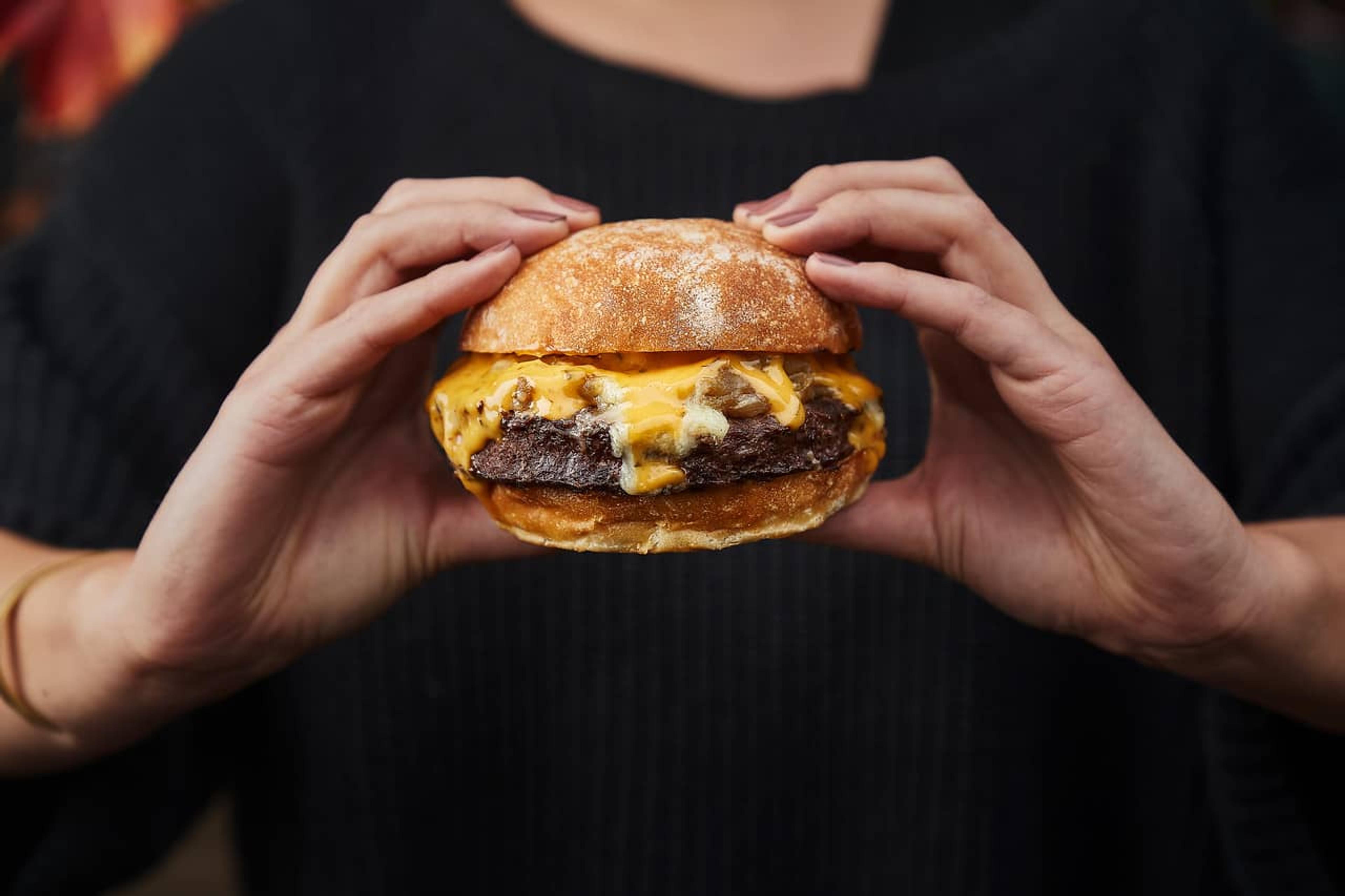 A person holding a cheeseburger.