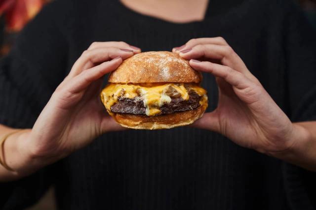 A person holding a cheeseburger.
