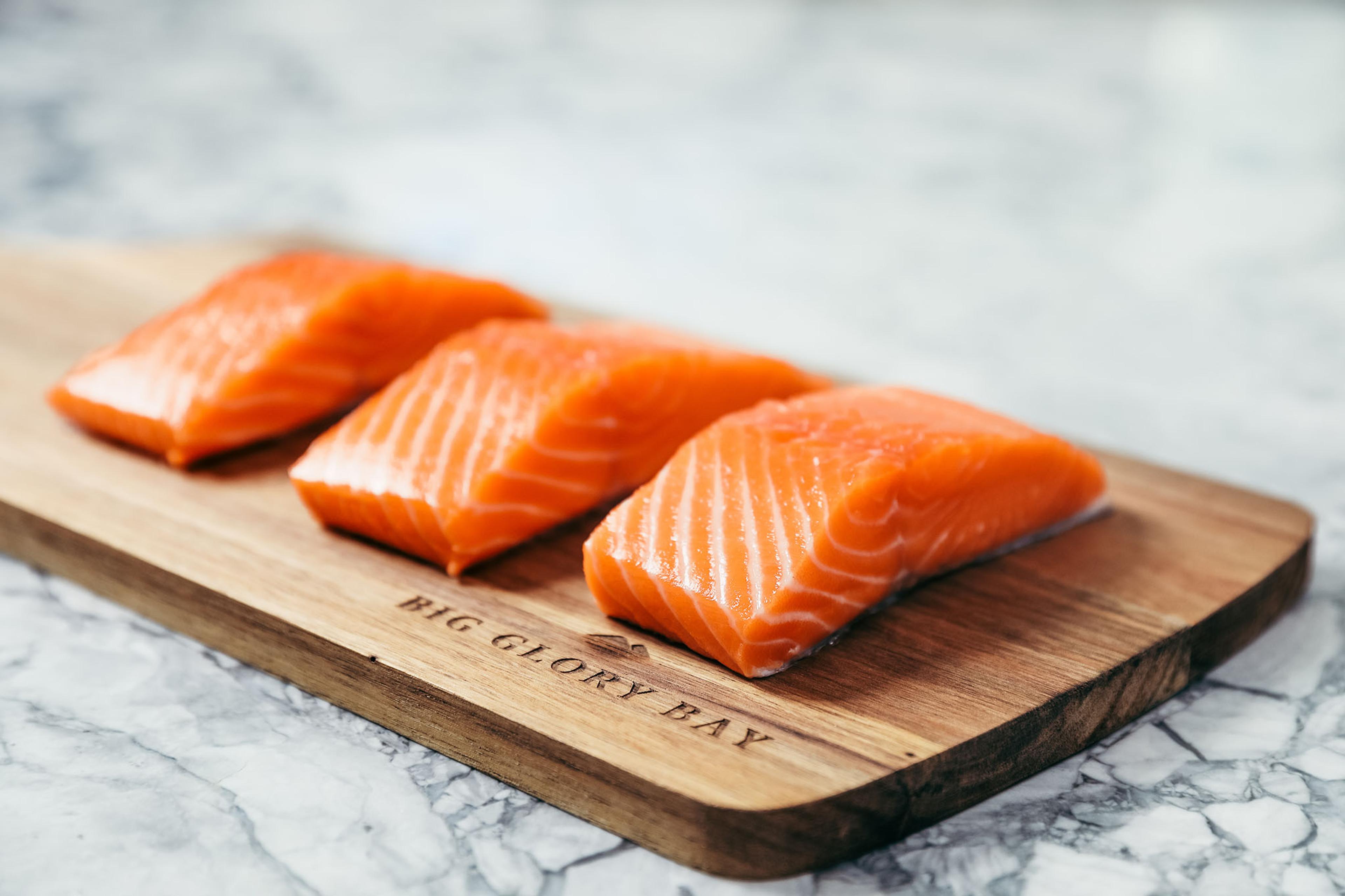 Raw salmon fillets on a wood plank.