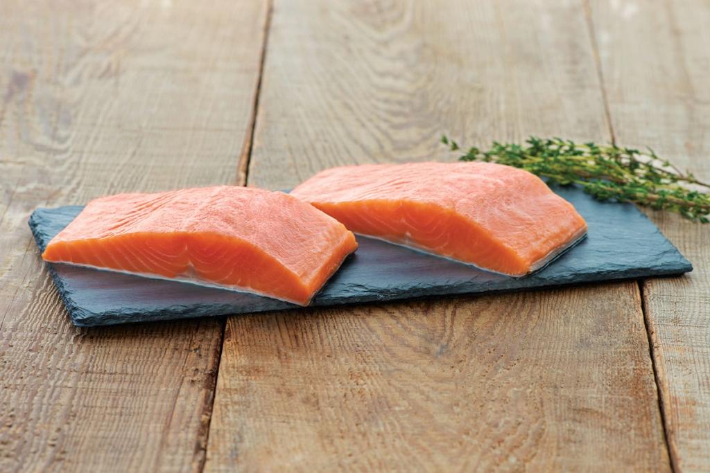 Raw salmon fillets on a stone slab with rosemary.