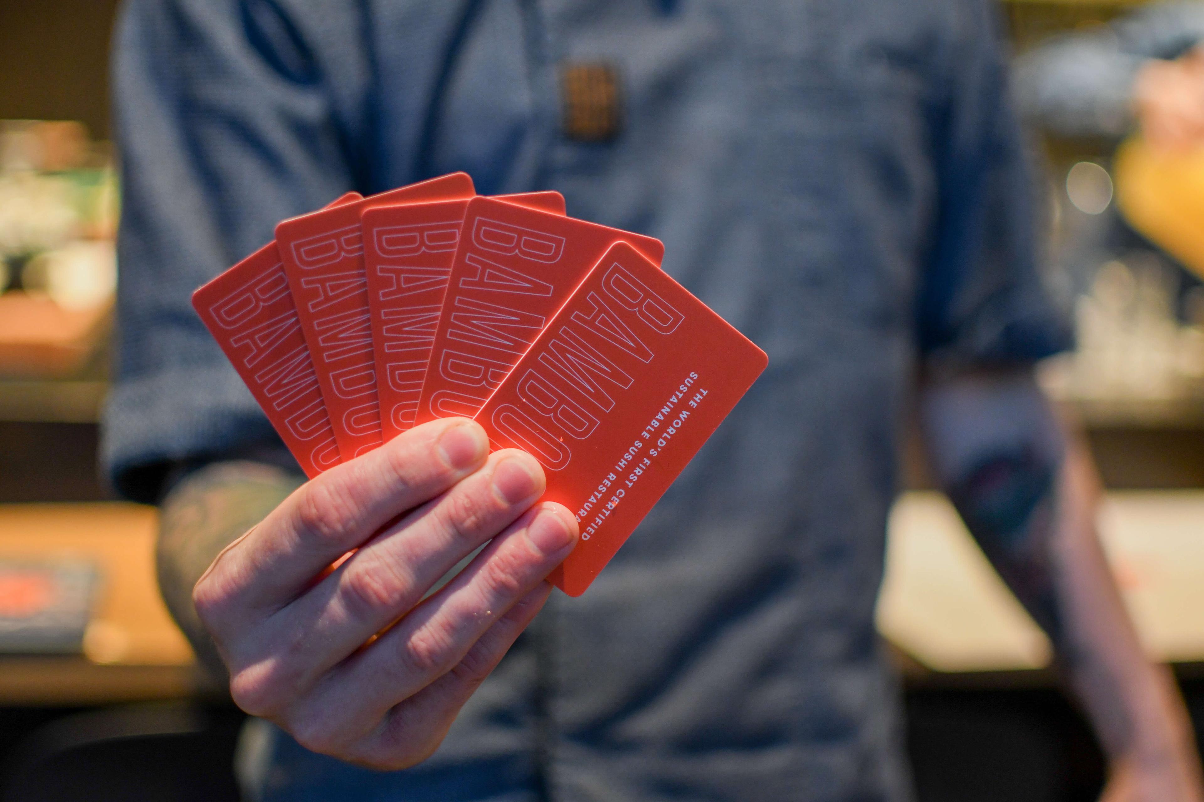 A person holding multiple Bamboo Sushi gift cards.
