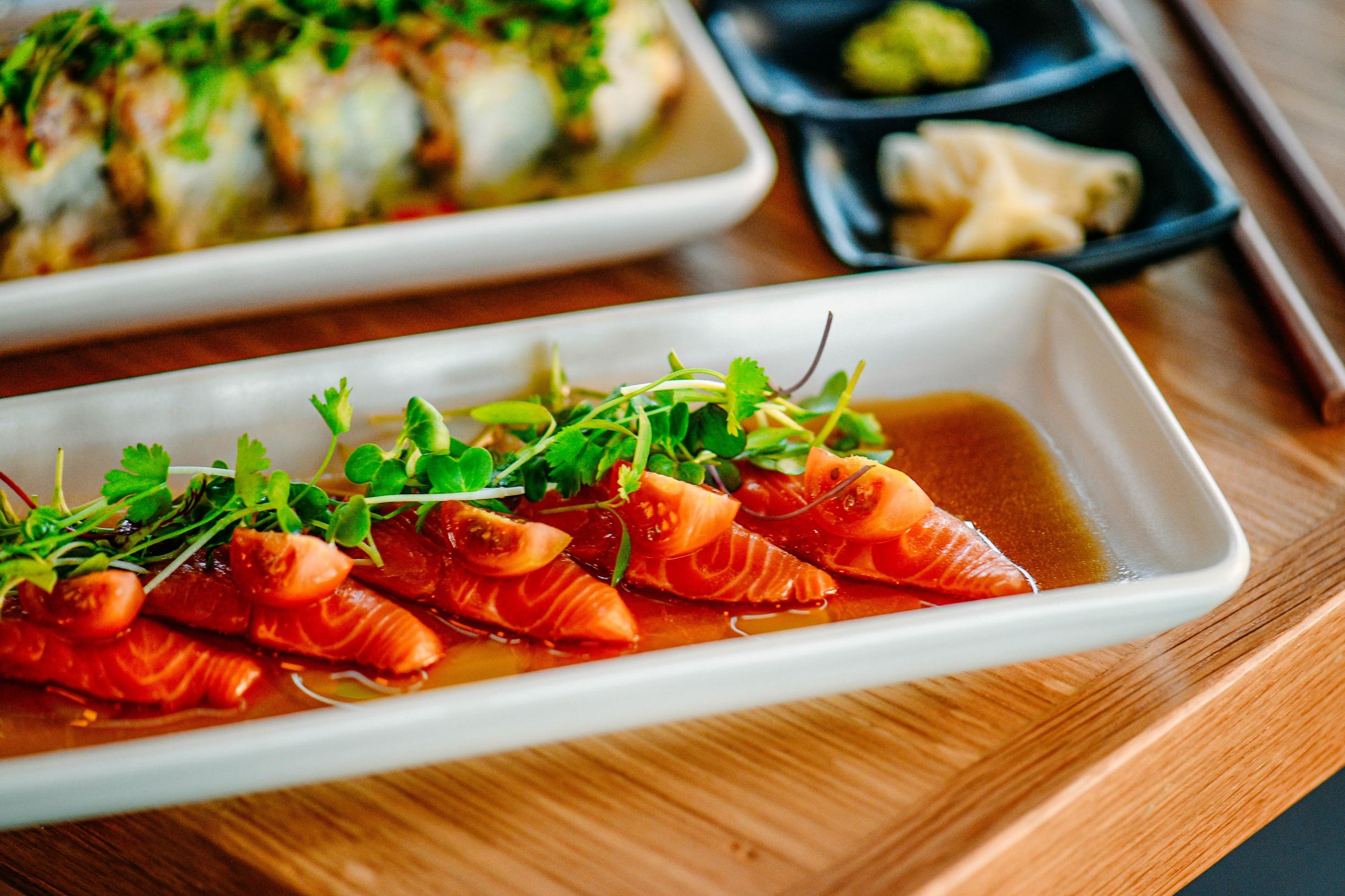 Salmon carpaccio with garnish of microgreens and tomato.