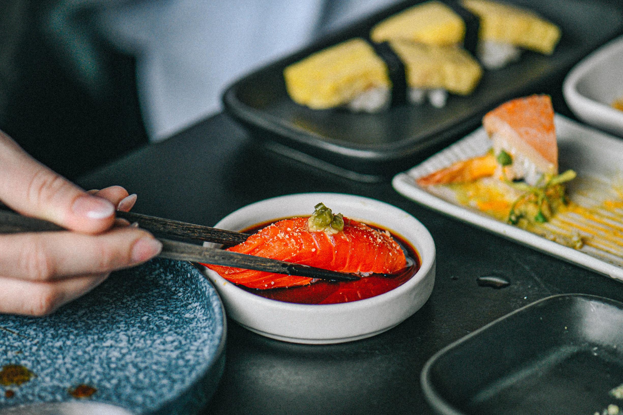 Sockeye nigiri being dipped in soy sauce.