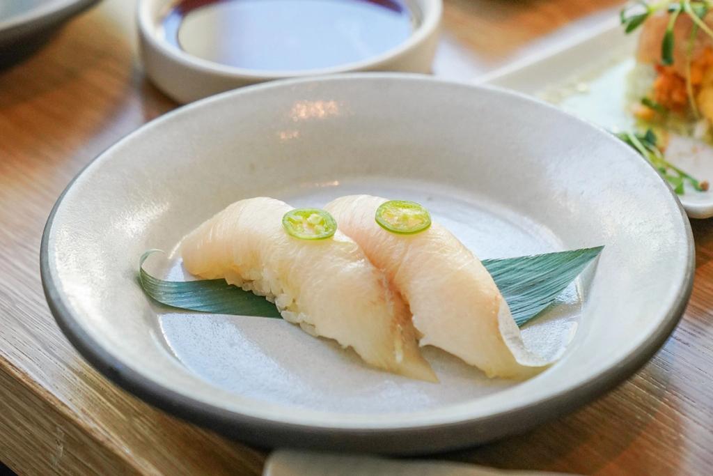 Hamachi nigiri in a dish with a garnish of jalapeno.