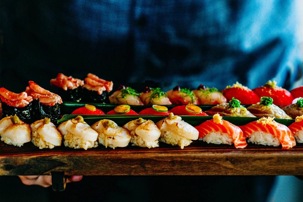 An array of sushi on a wood board.