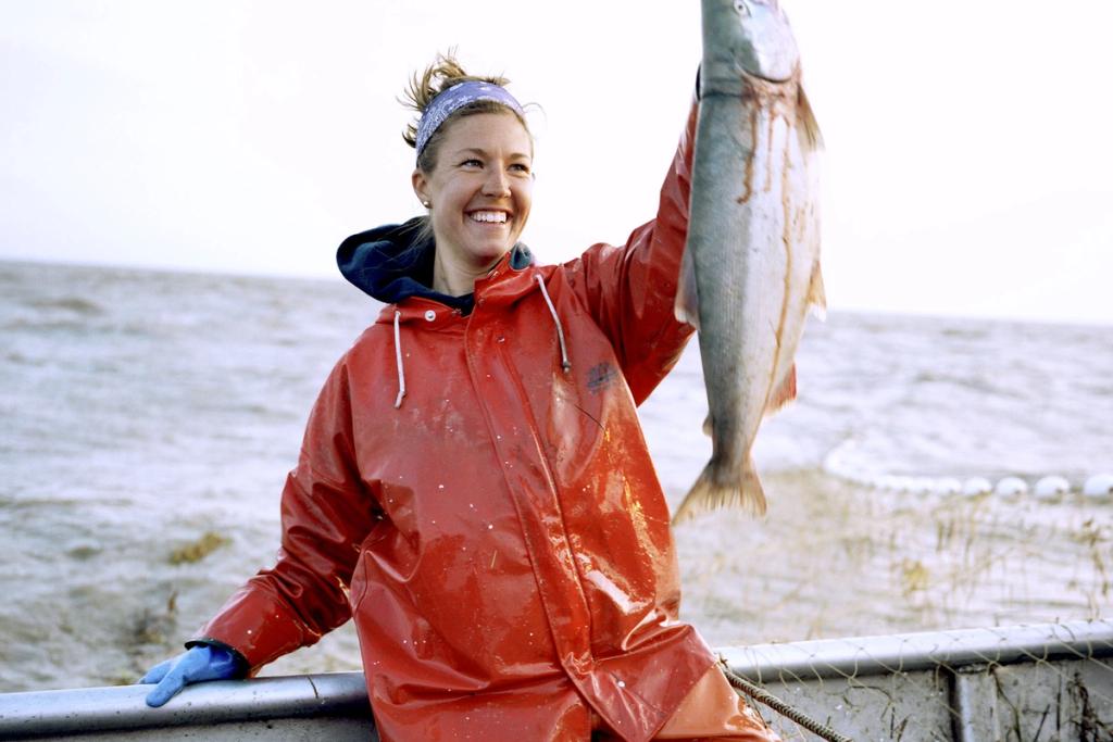 Iliamna Fish Co Female Employee holding up a large fish.