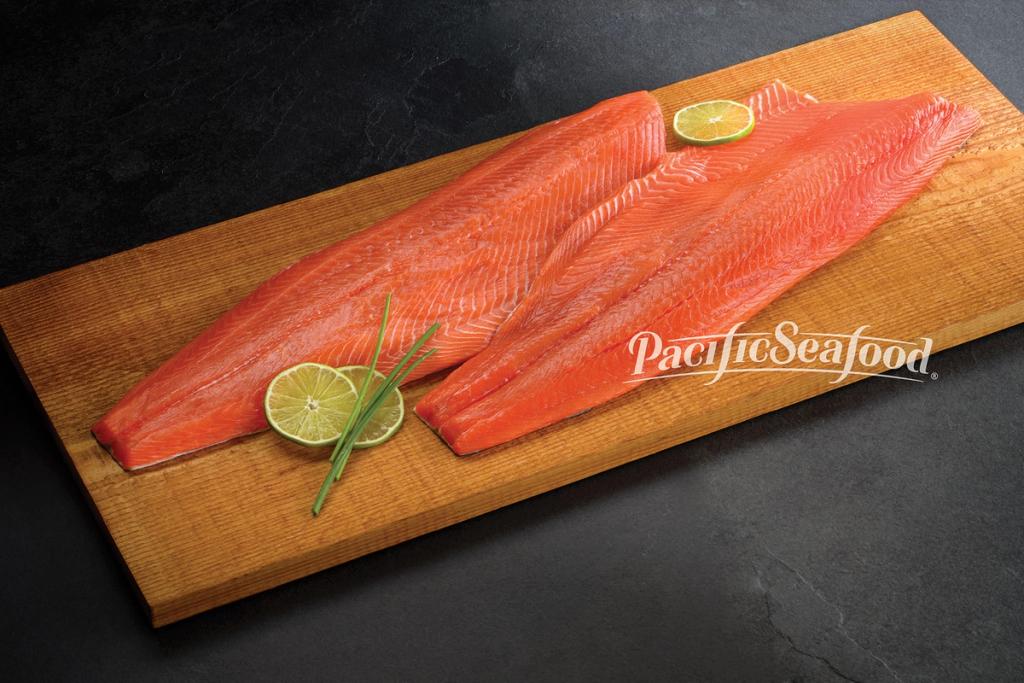 Raw Salmon on a wood board with lime and chives.