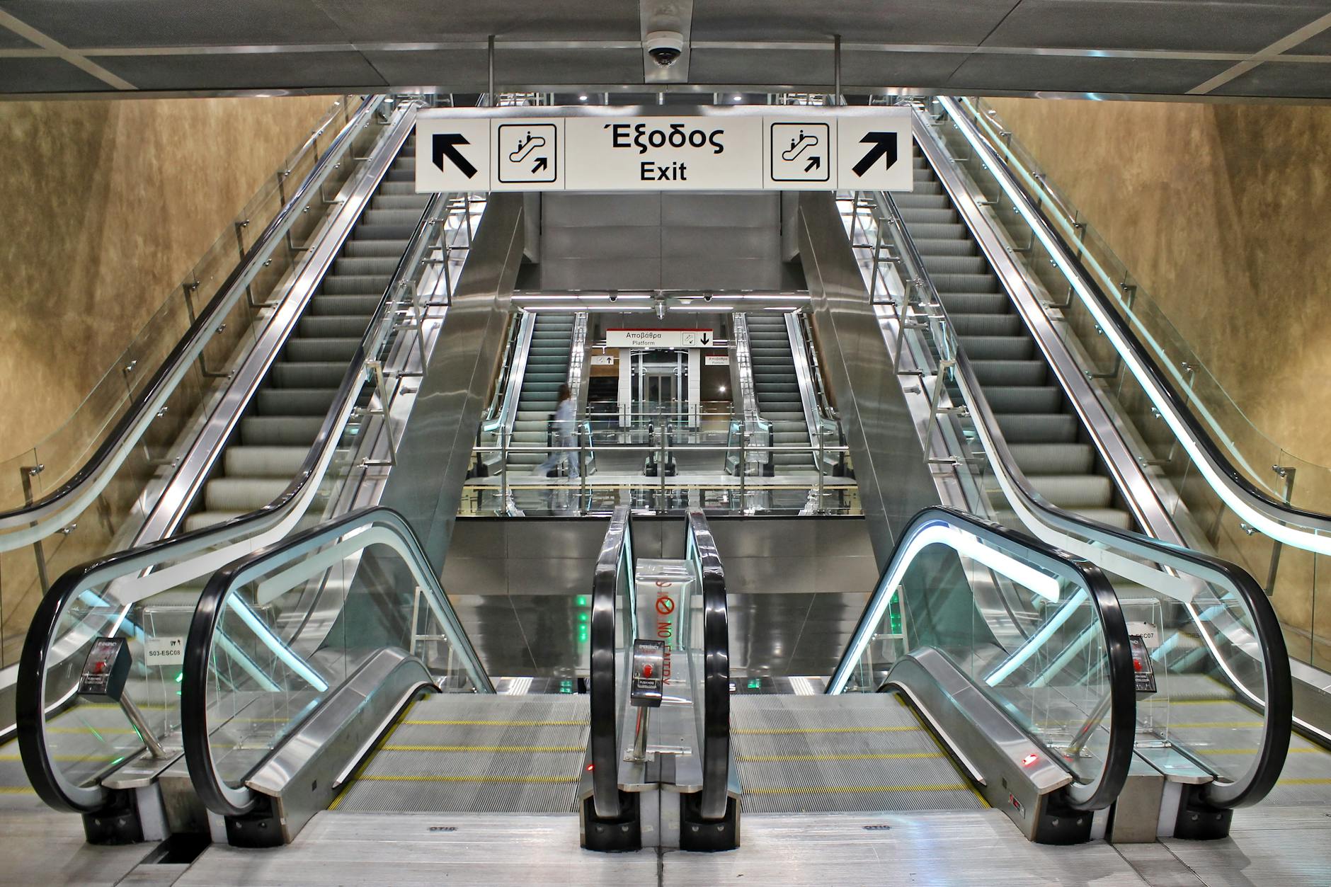 A person waiting for a train at a station, looking at transit signage.