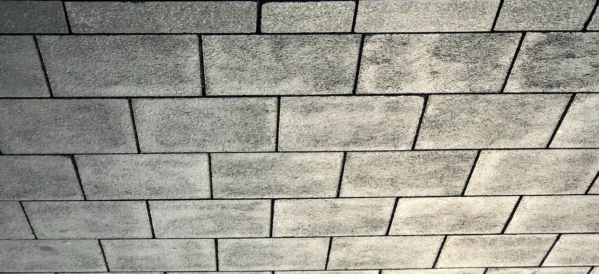 A close up picture of a sidewalk pattern with a shadow of two people