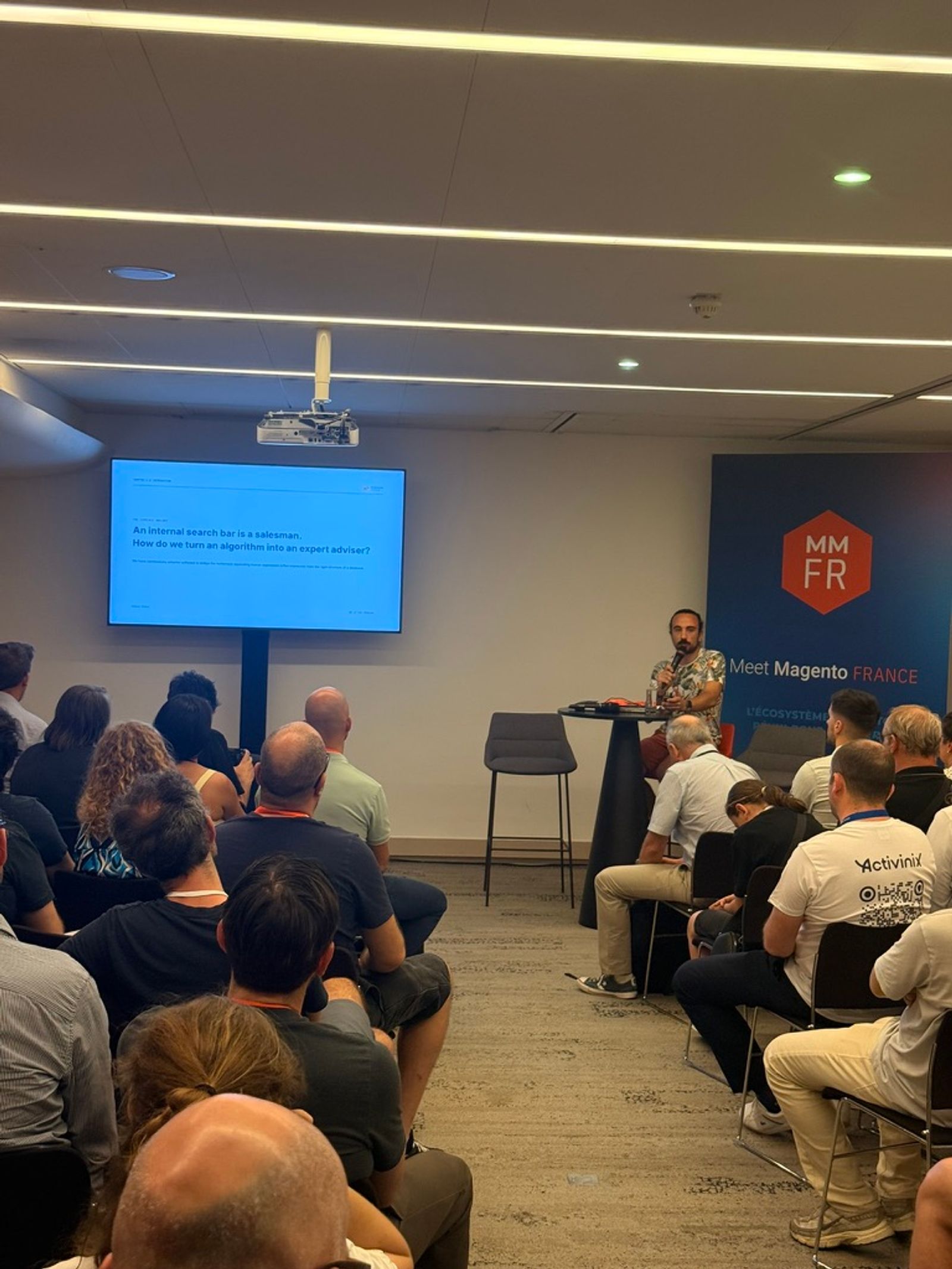 Romain Ruaud of ElasticSuite on stage at MM France 2026 presenting the slide: An internal search bar is a salesman. How do we turn an algorithm into an expert adviser?