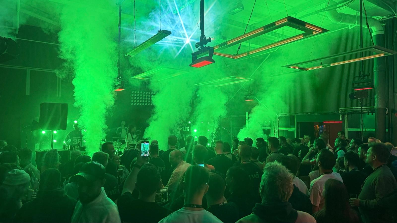 The Meet Magento Netherlands 2025 afterparty at LIEF Amsterdam, with a full room and green lights.