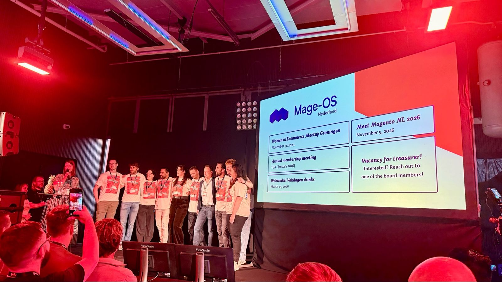 The Mage-OS Nederland team on stage at the close of Meet Magento Netherlands 2025, next to the slide with upcoming events, including Meet Magento NL 2026 on 5 November 2026.