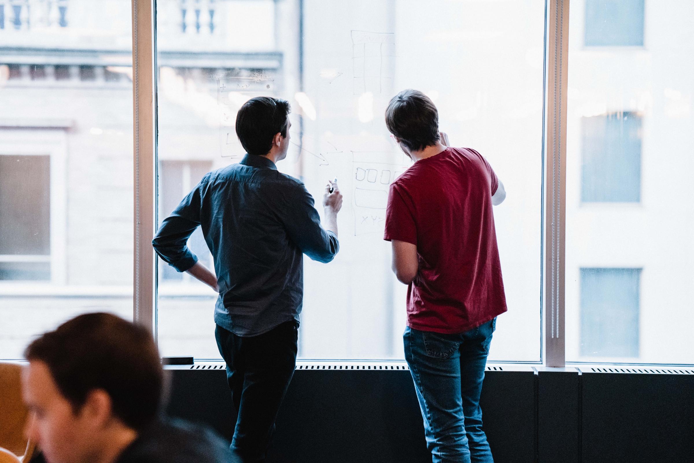 Brian and Grant whiteboarding on a window.