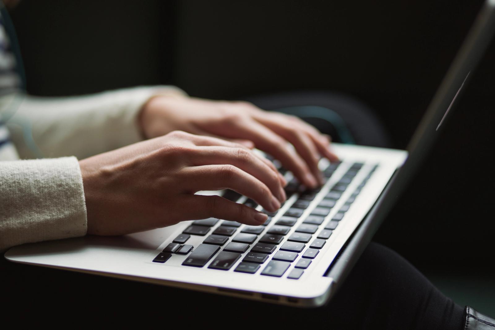 Two hands typing on a laptop keyboard