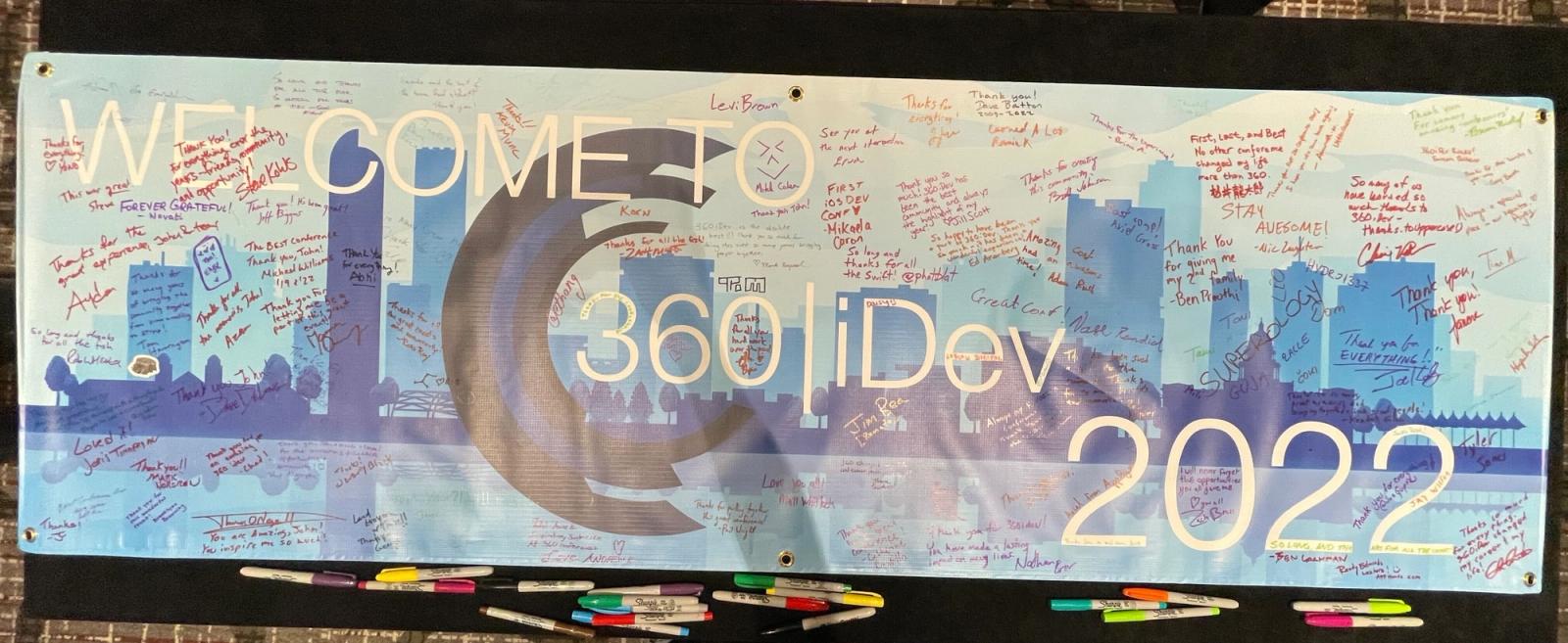 A photo of the 360iDev banner that says "Welcome to 360iDev 2022" and has lots of signatures on it.