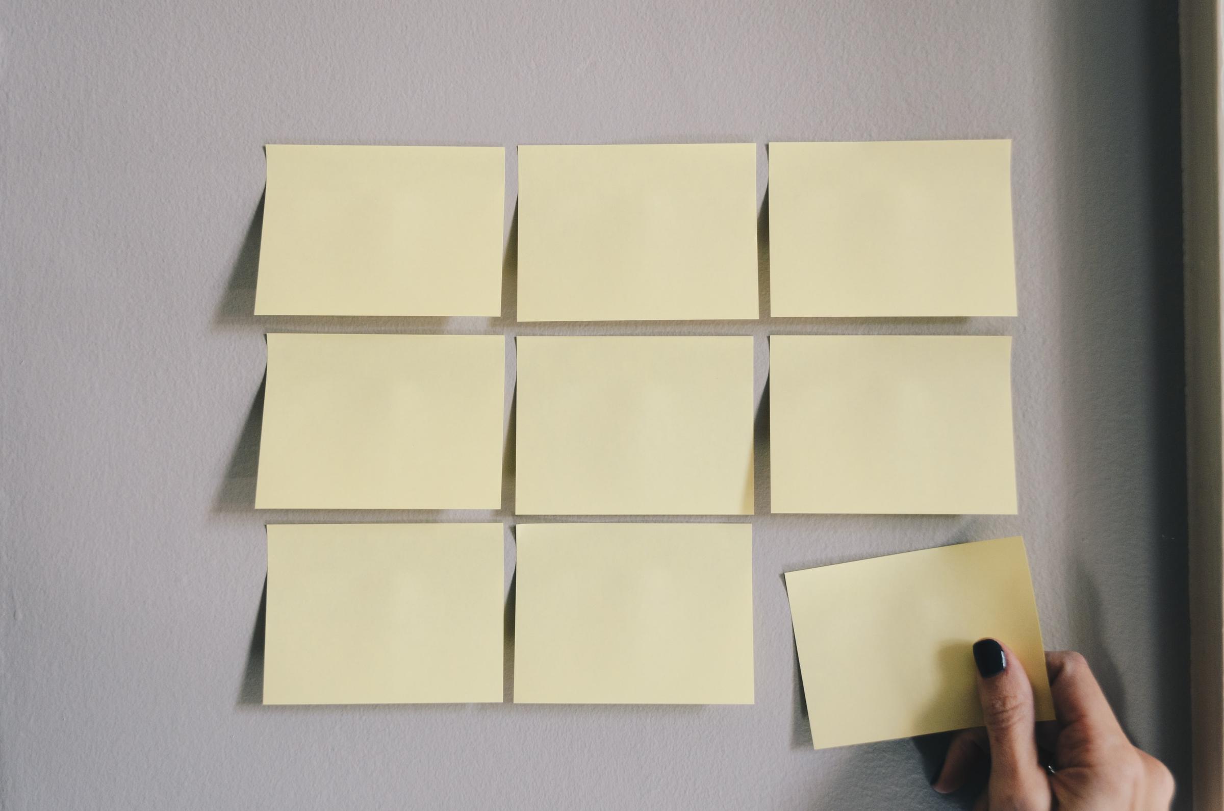 A grid of yellow sticky notes stuck to a wall.