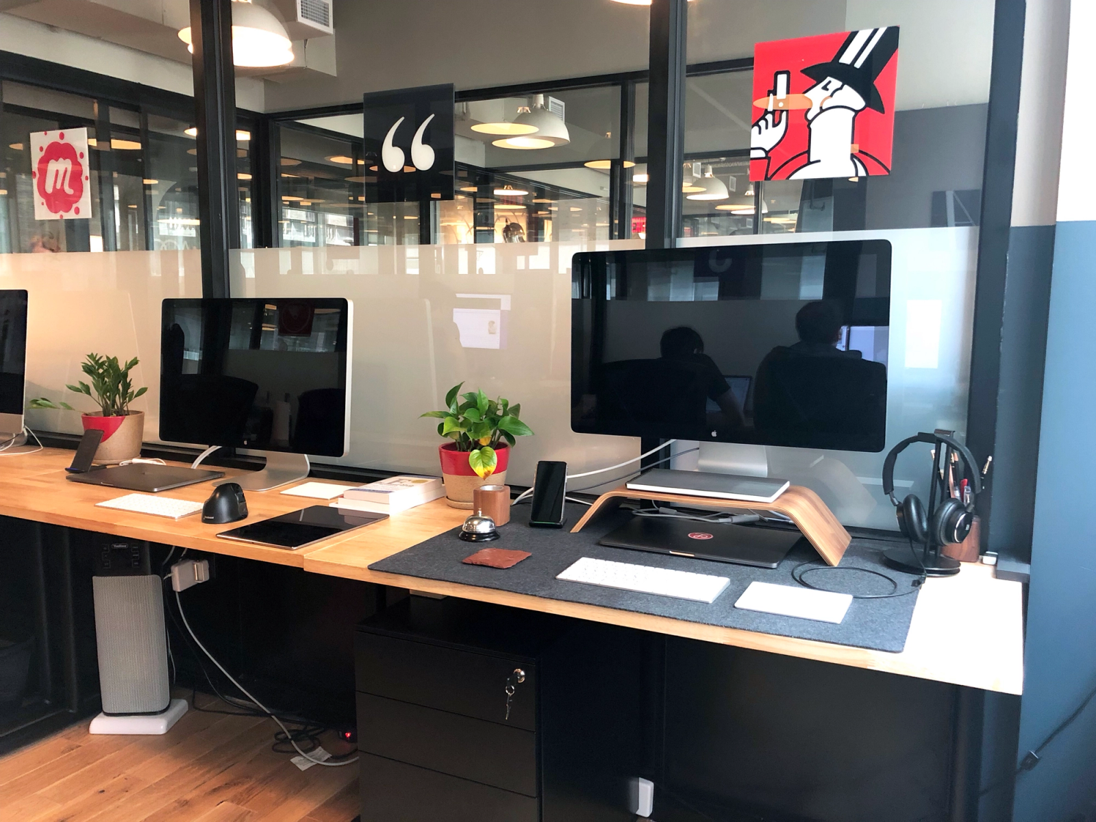 Two desks at the Lickability office with some app icon artwork hung above them.