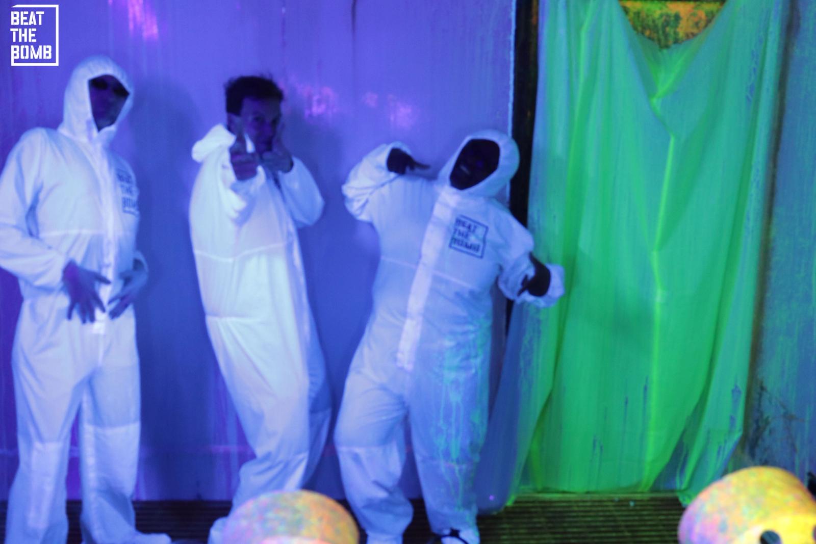 Three Lickability employees wearing white hazmat suits covered in paint, posing to celebrate their win