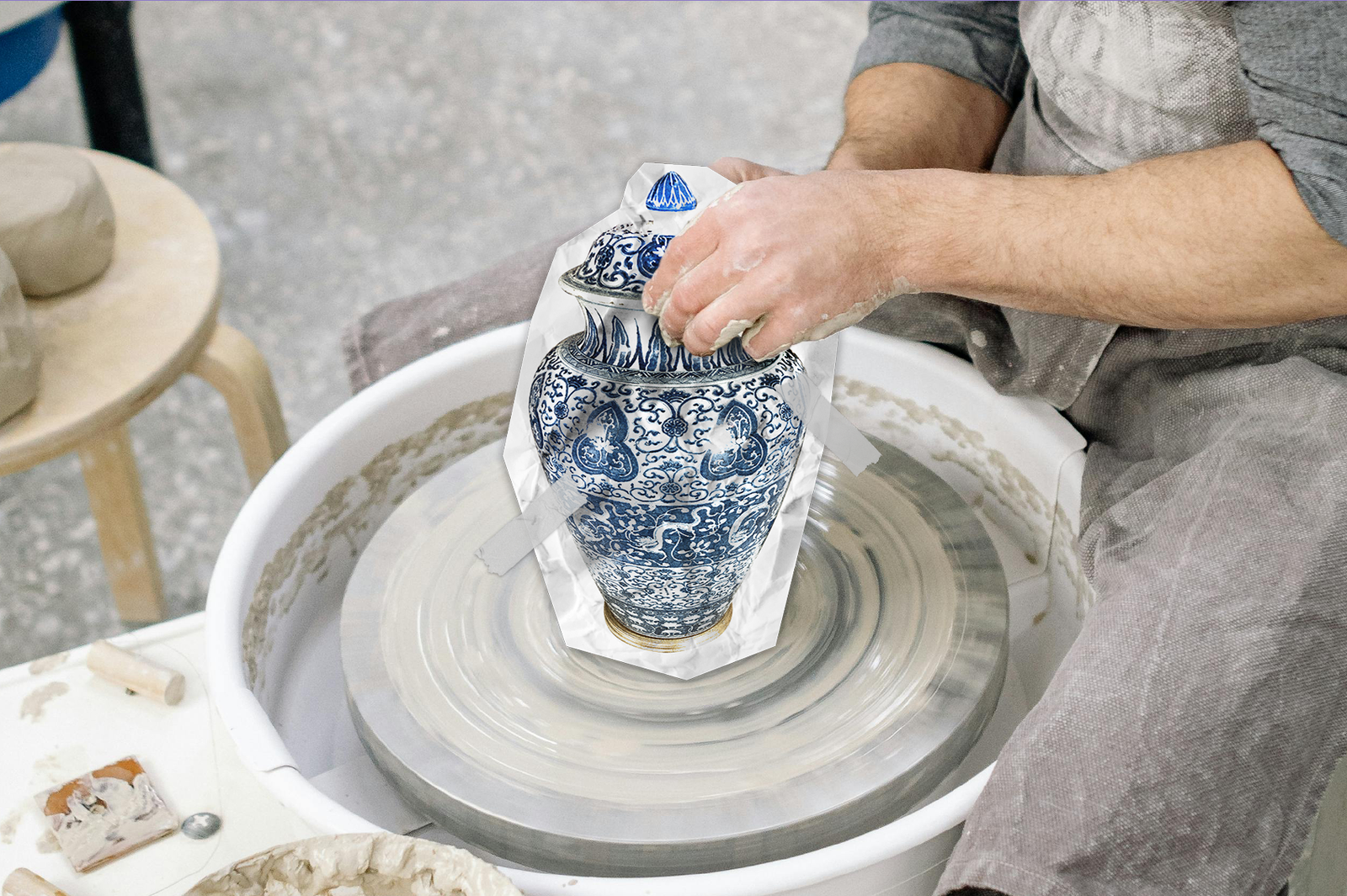 A potter sitting at a potter's wheel, but instead of making a vase from clay, a complete Ming vase is in its place.