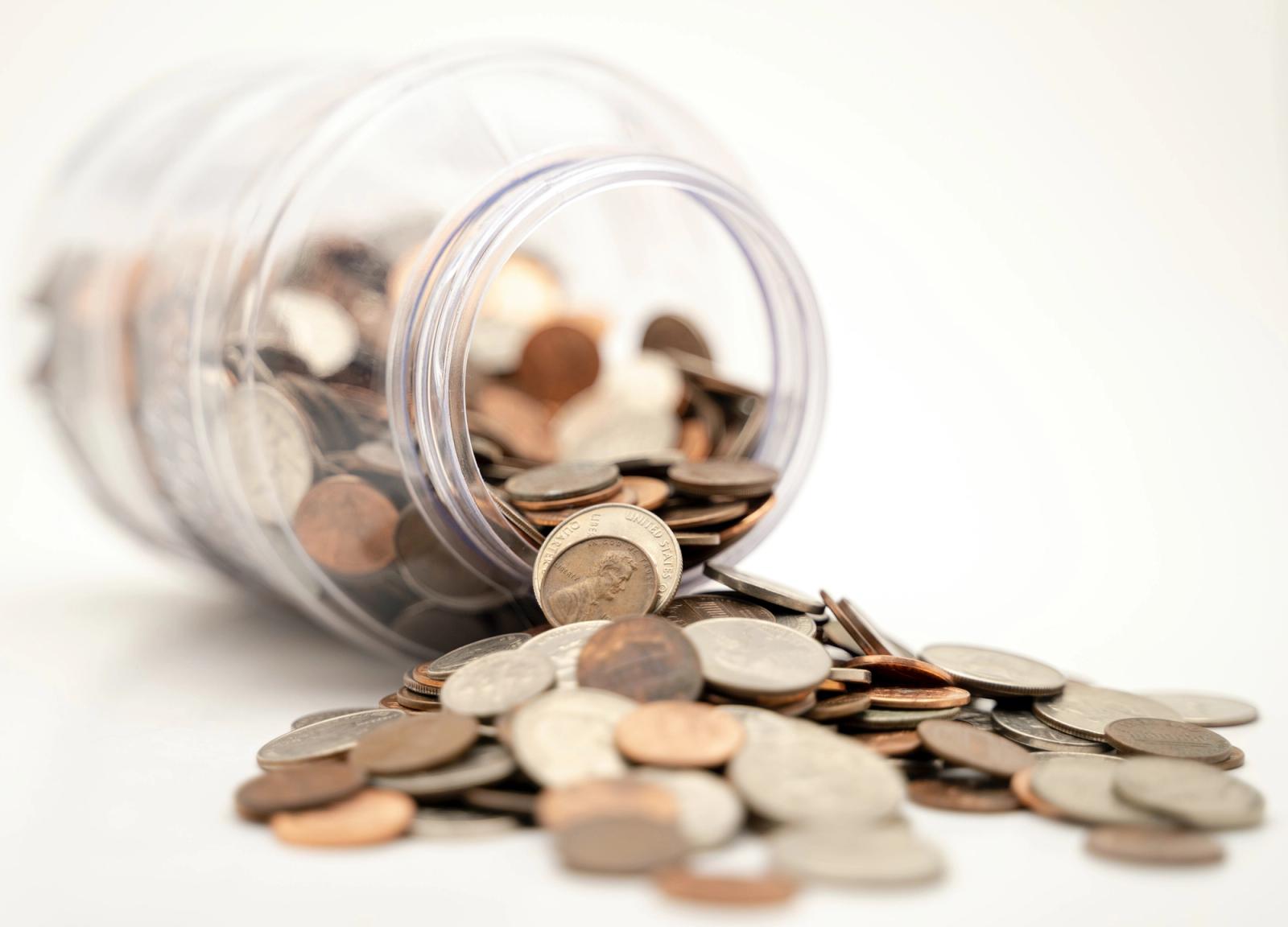 A glass jar full of coins tipped over.