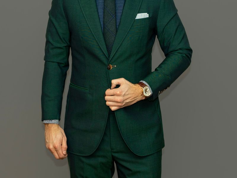 Man in a green tailored suit photographed against grey