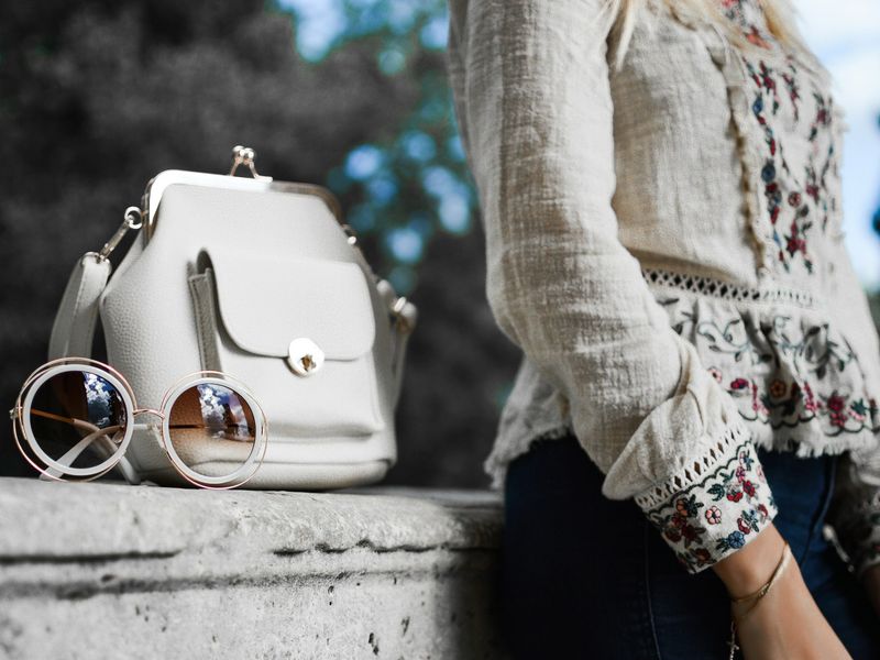 White structured handbag resting on a stone ledge
