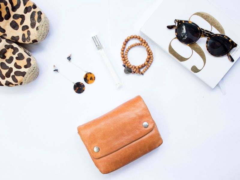 Flat lay of a tan wallet, sunglasses and jewellery