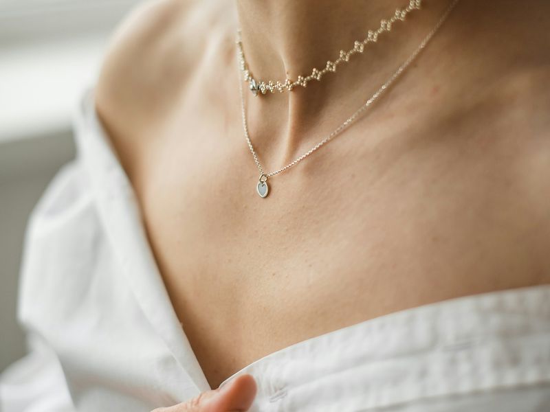 Layered gold necklaces on a bare shoulder