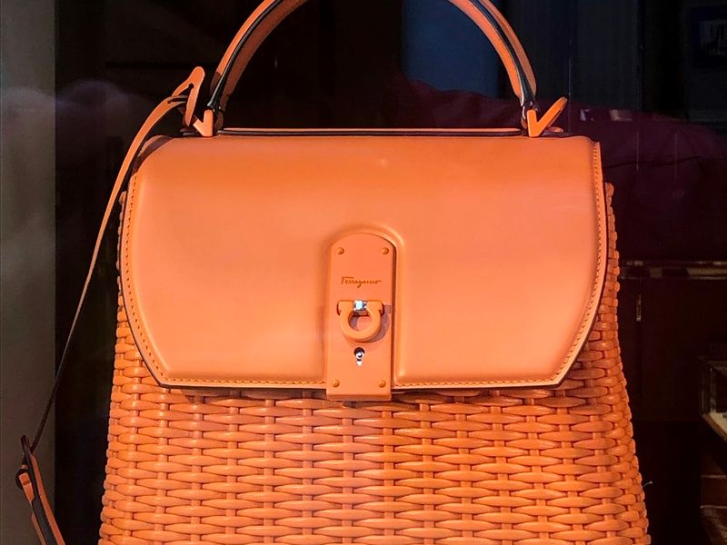 Woven orange handbag lit against a dark background
