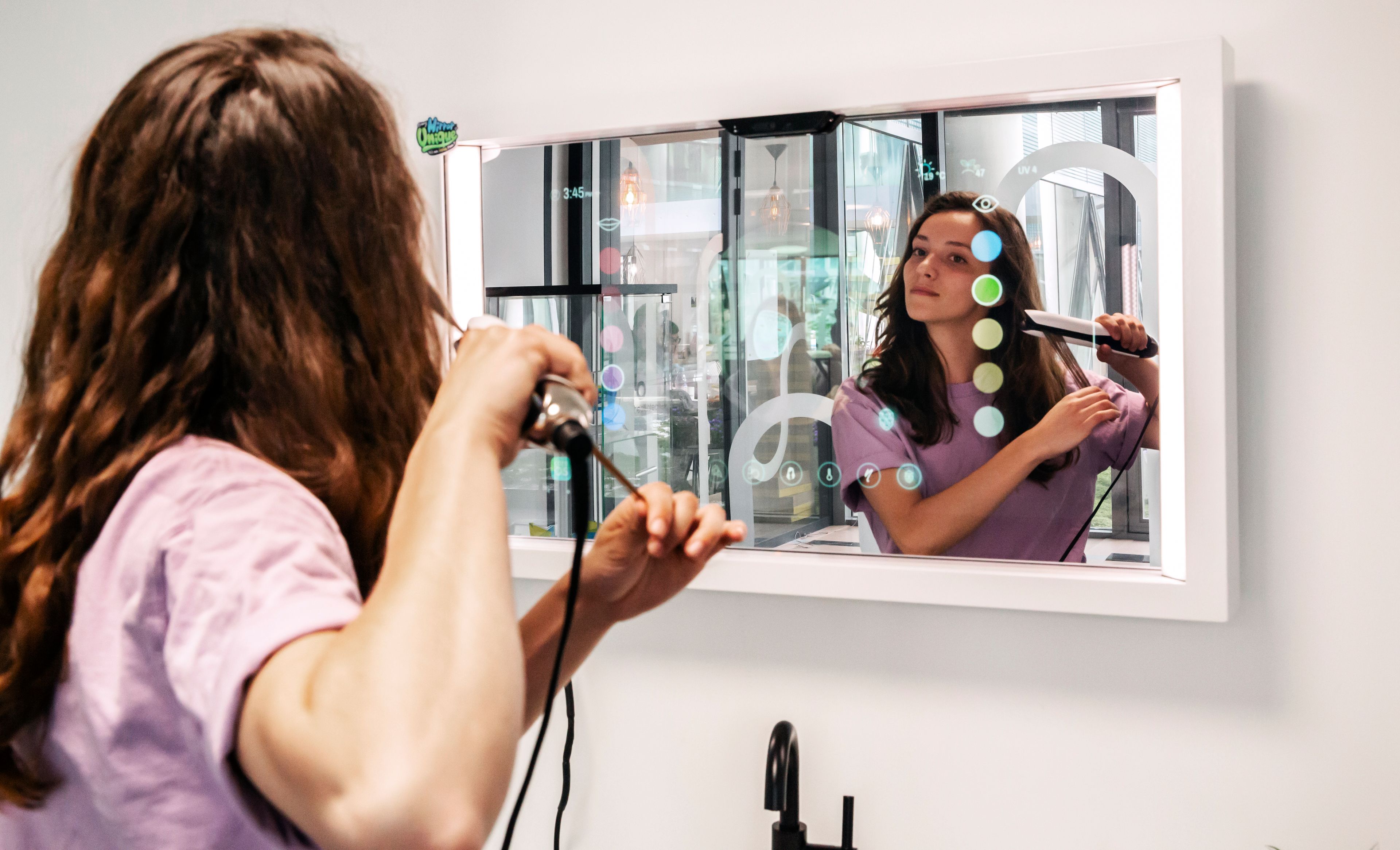 Woman straightening hair looking at connected beauty mirror