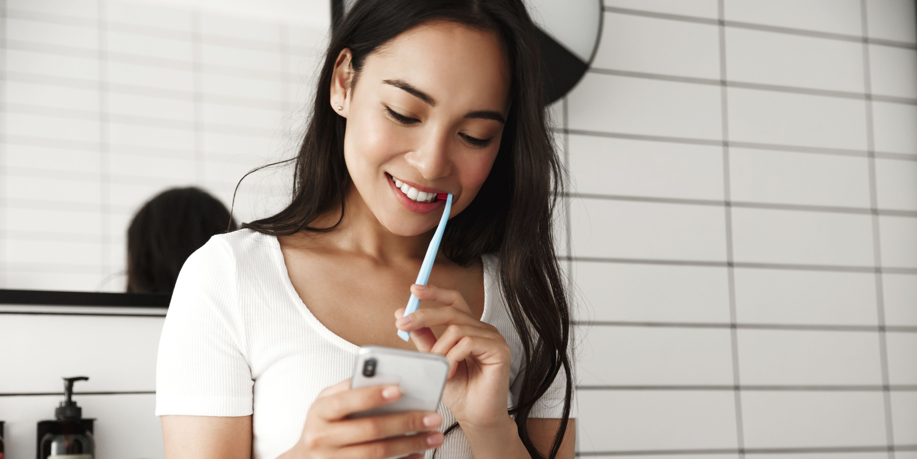 Une femme regarde son téléphone pendant qu'elle se brosse les dents