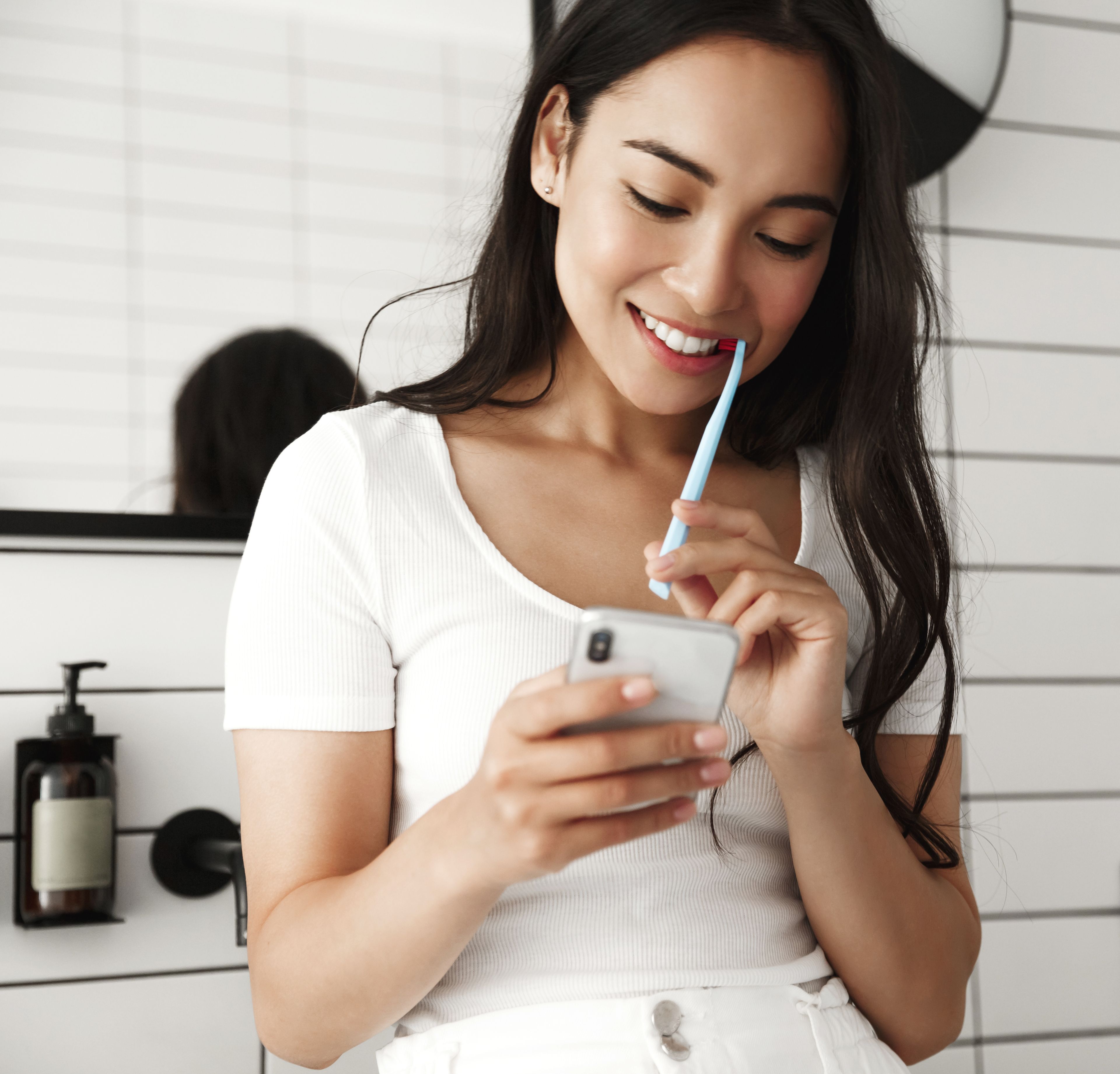 Girl brushing her teeth with smartphone