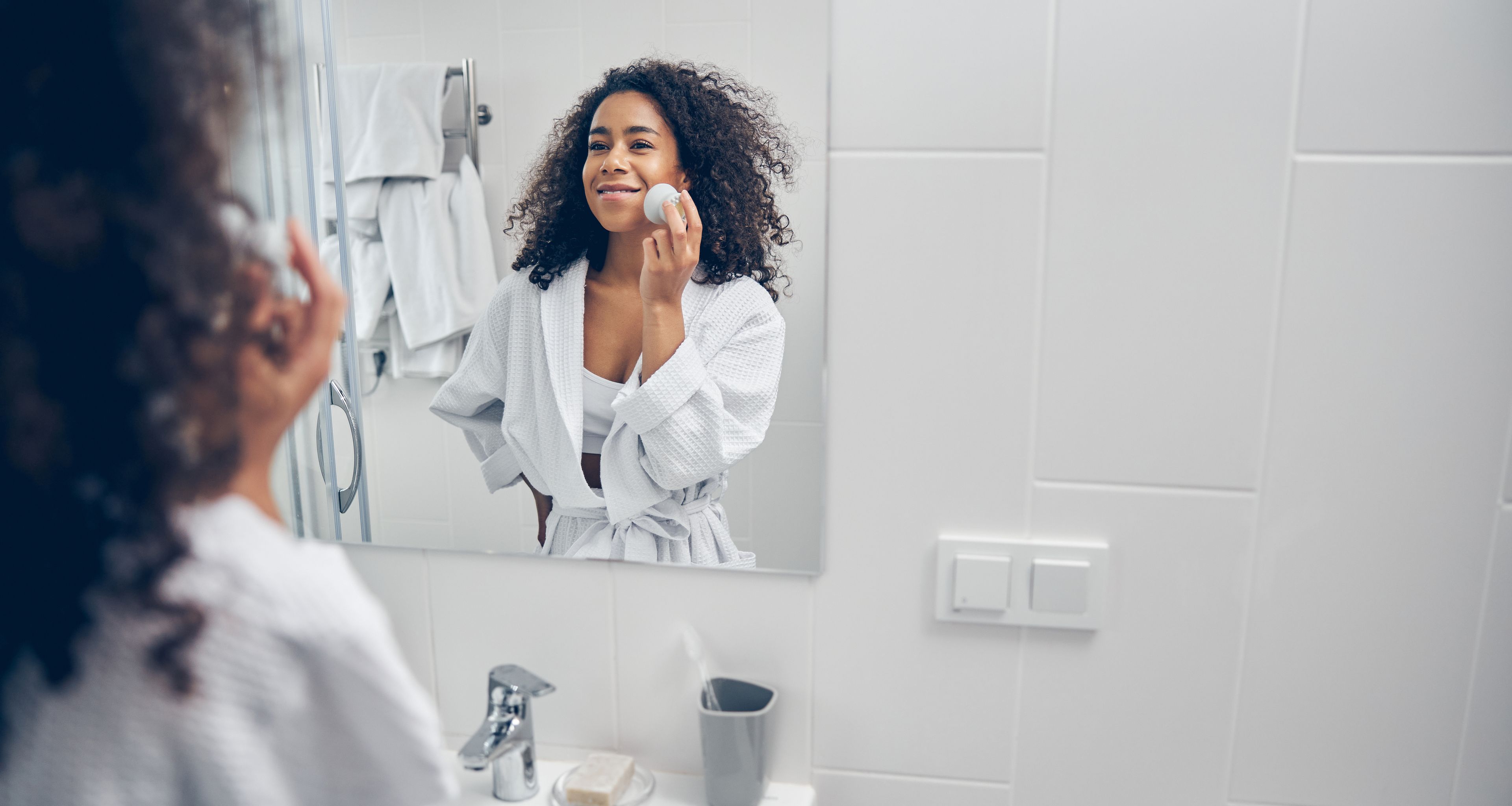 Woman looking in bathroom mirror during skin routine