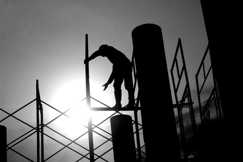 Image of a worker on scaffolding that is backlit